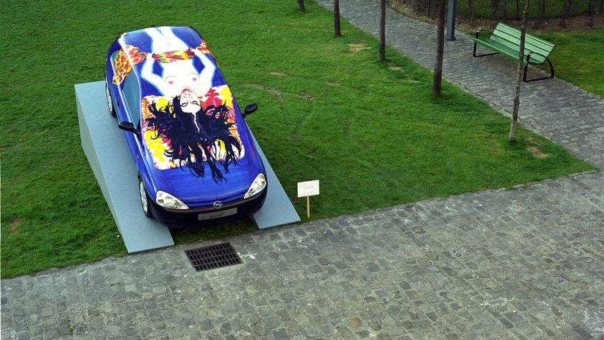 photographie d'une voiture/sculpture placée dans le parc de la maison des arts